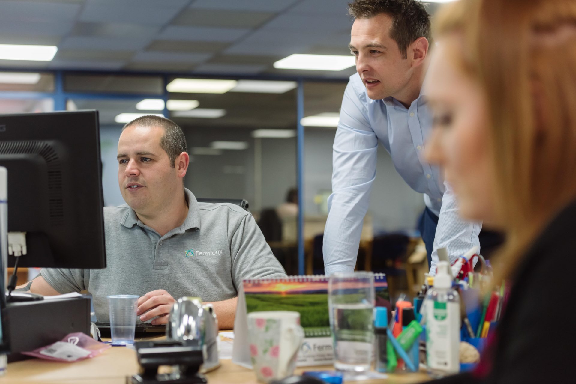 Two male FermionX workers working at their desks