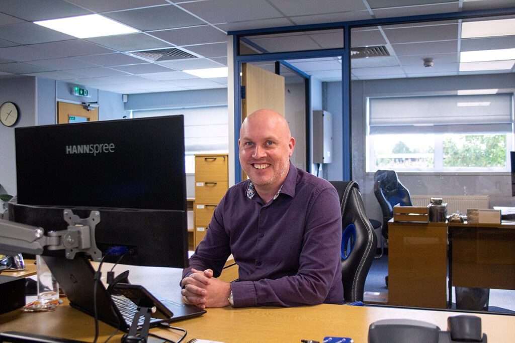 FermionX worker smiling and working at their desk